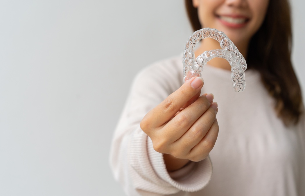 close up woman hand holding dental aligner retainer (invisible) on background for beautiful teeth and dental treatment course concept